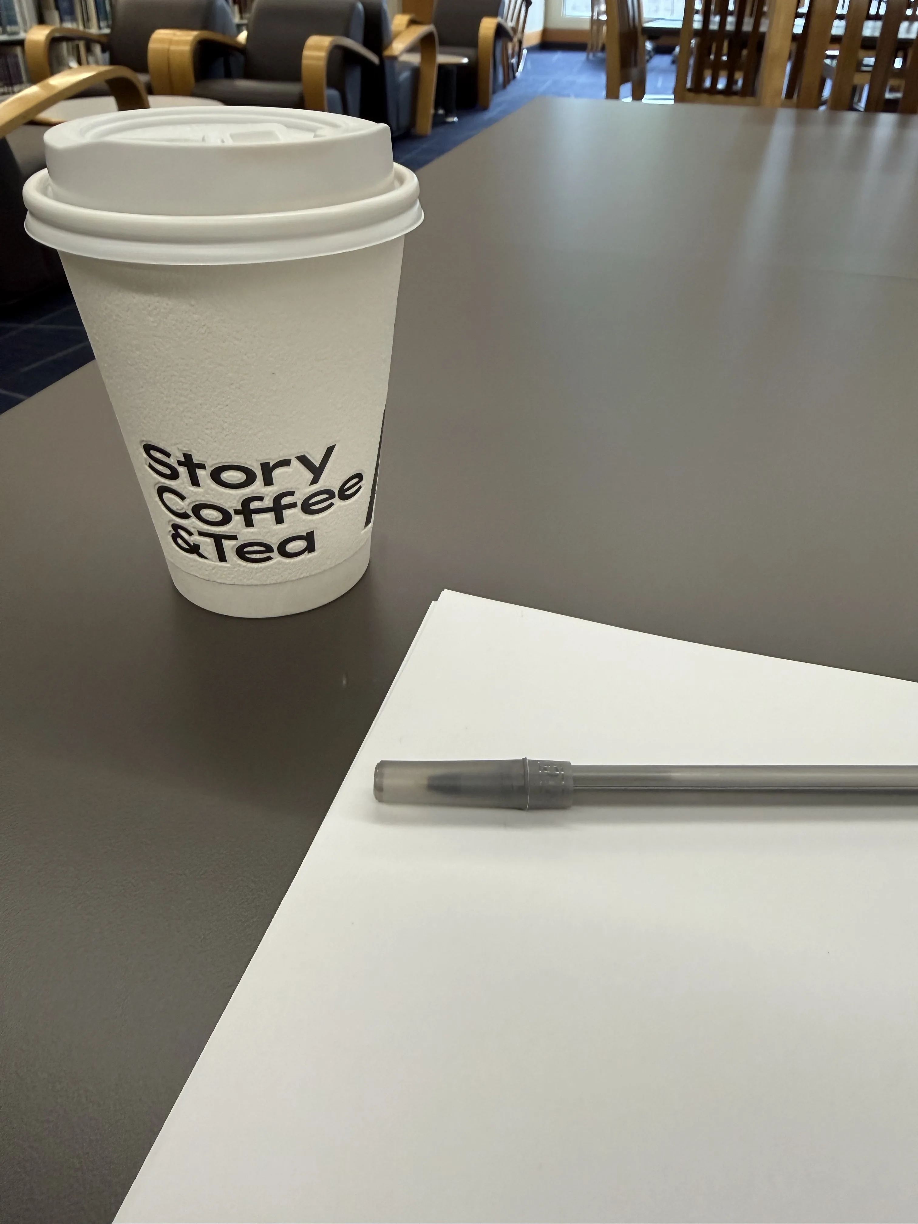 A Story Coffee cup beside my handwritten notes at the library